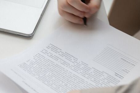 Signature Style - Faceless male worker with paper document near laptop on desk