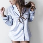 Pajama - woman in white and black button-up coat leaning on wall